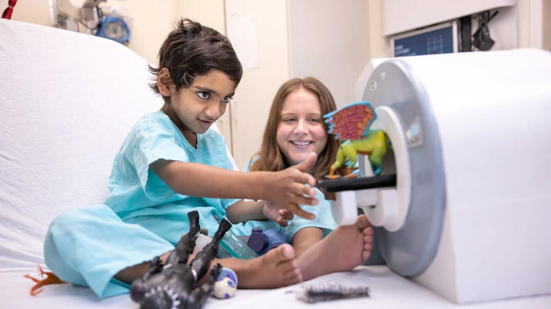 child holding teddy bear in hospital bed
