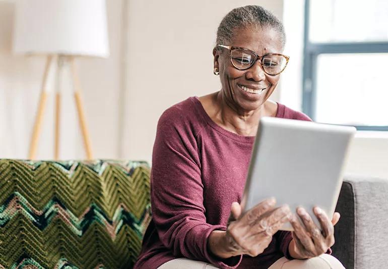 Someone smiles while they read something on their tablet.