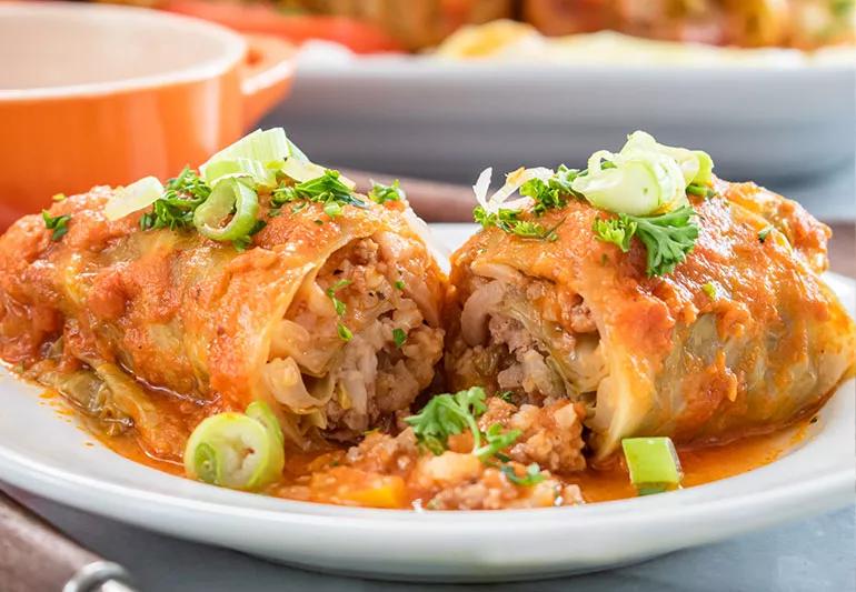 A turkey and beef stuffed cabbage roll cut in half on a plate
