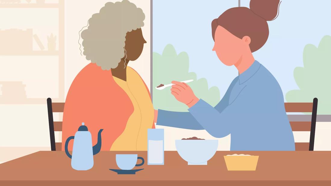 An illustration of a person helping another person eat with a spoon