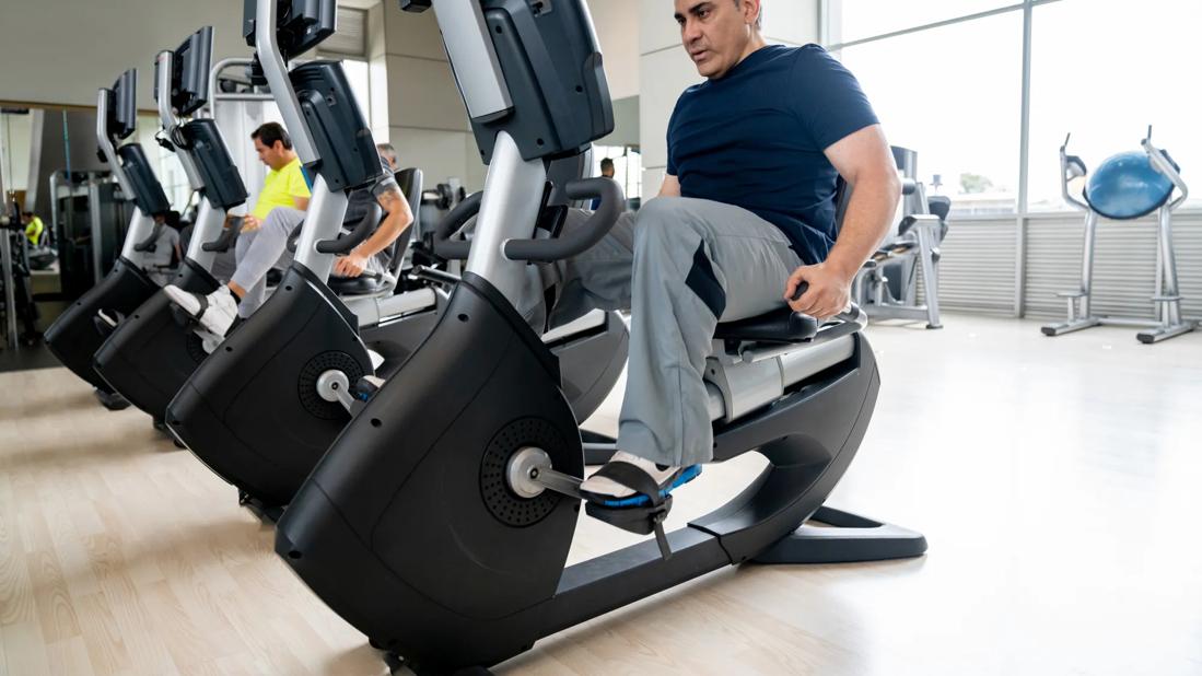 Person using recumbent stationary bike at gym facility