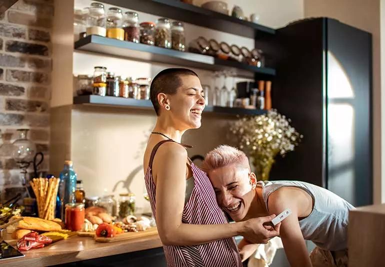 Couple celebrating in kitchen with positive pregnancy test.