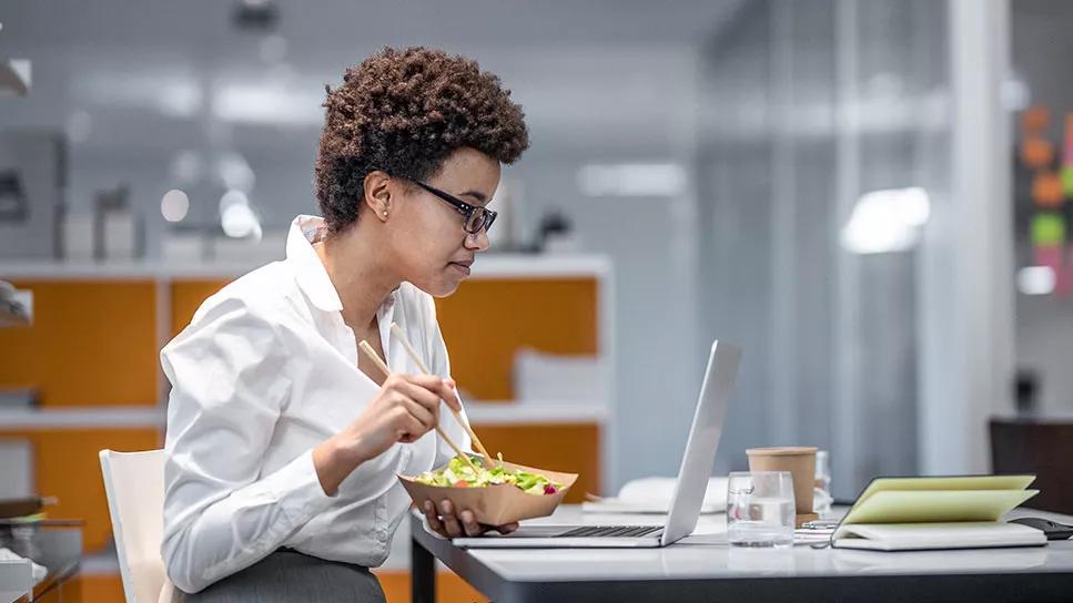 person eating a small lunch alone at desk at the office