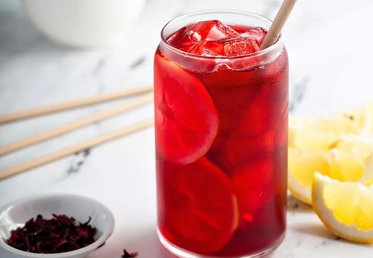 A glass of iced hibiscus tea with lemon slices
