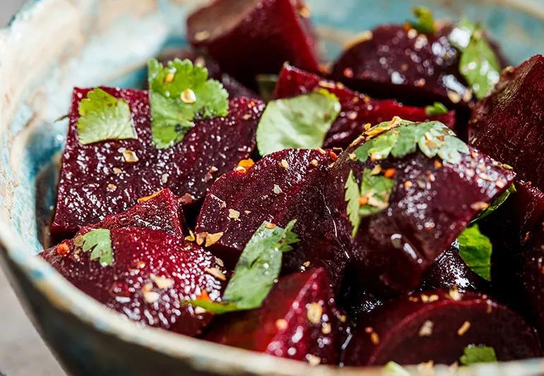 Decorative bowl filled with beets covered in orange zest and herb garnish