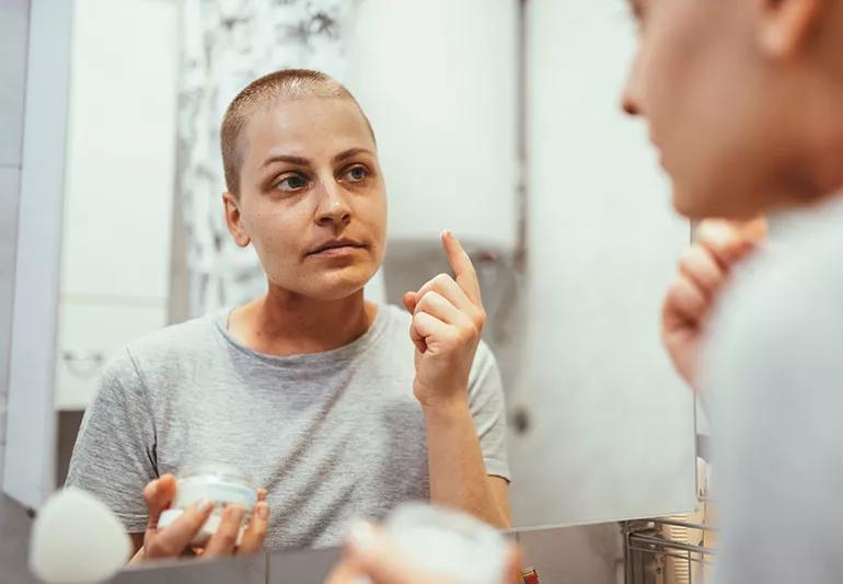 A patient with cancer is applying skin cream.