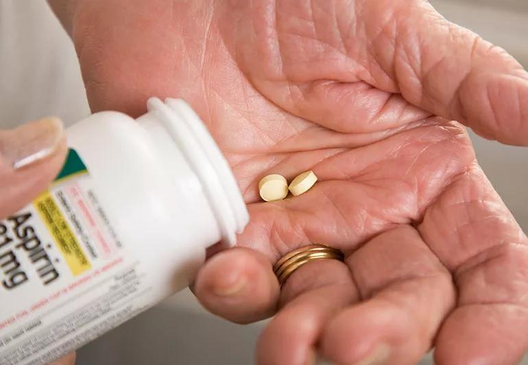 Older woman taking aspirin for pain instead of NSAID