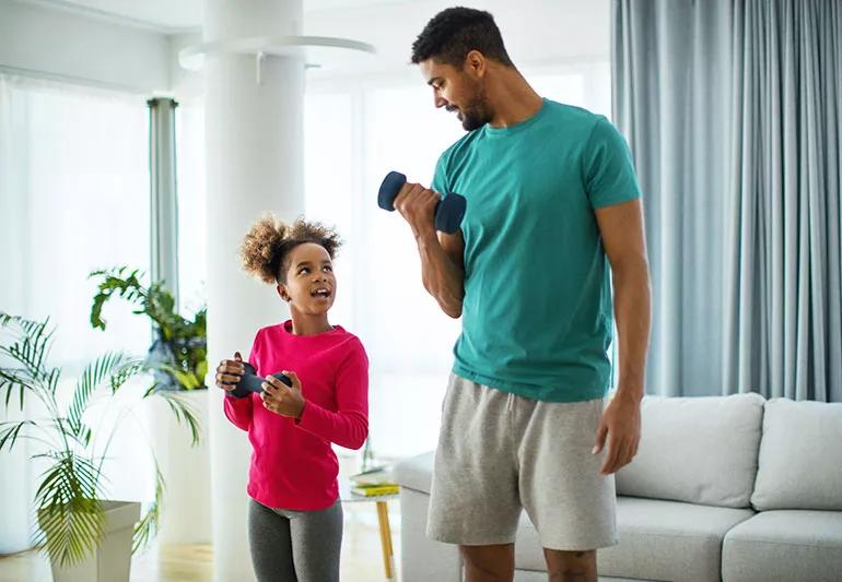 An adult and a child exercising together by lifting small hand weights