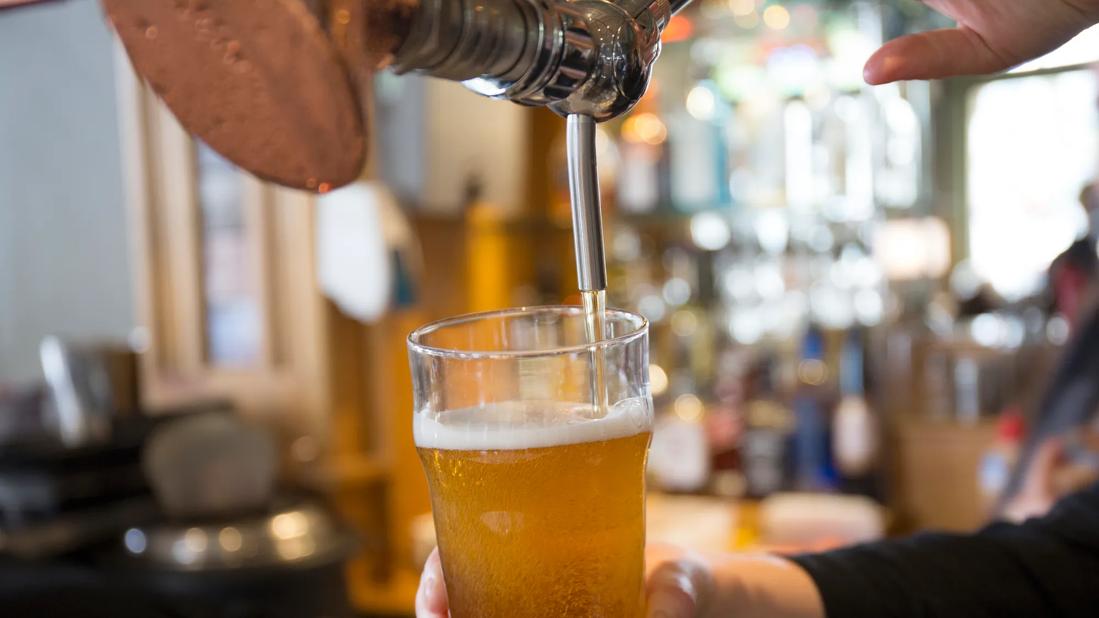 Glass of draft beer being poured at a pub