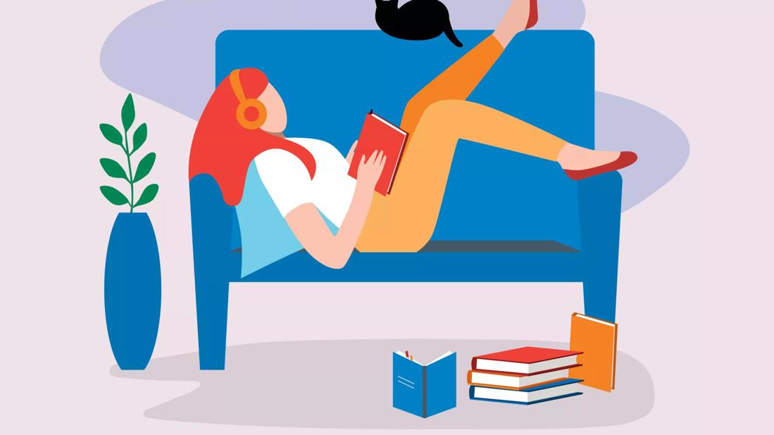 person lying on couch with headphones and reading a book alone