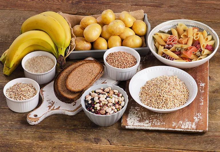 A table full of foods including bananas, pasta, bread and beans