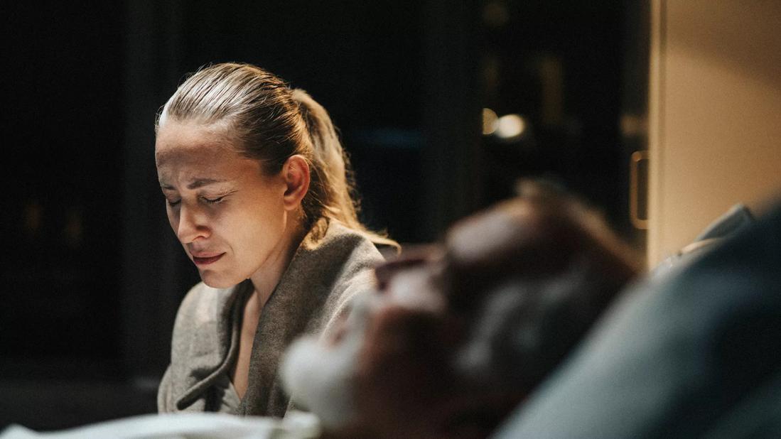 Angusihed person sitting by hospital bedside of loved one