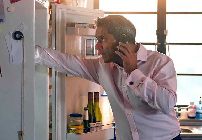 Man looking in refrigerator to find unspoiled food after power outage