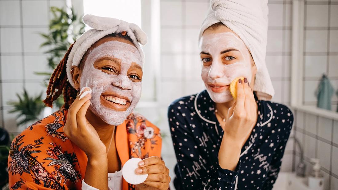 Two happy people in pjs with faces covered in white skin care products