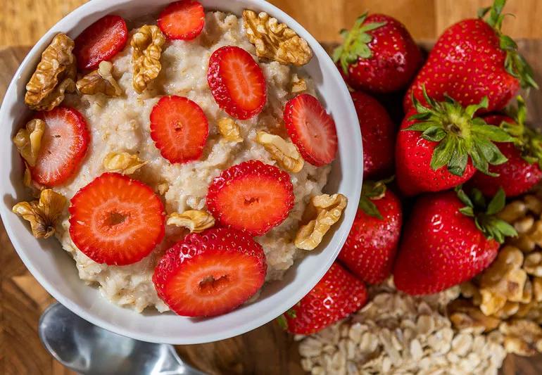Overhead view of bowl of oatmeal topped with strawberries and nuts