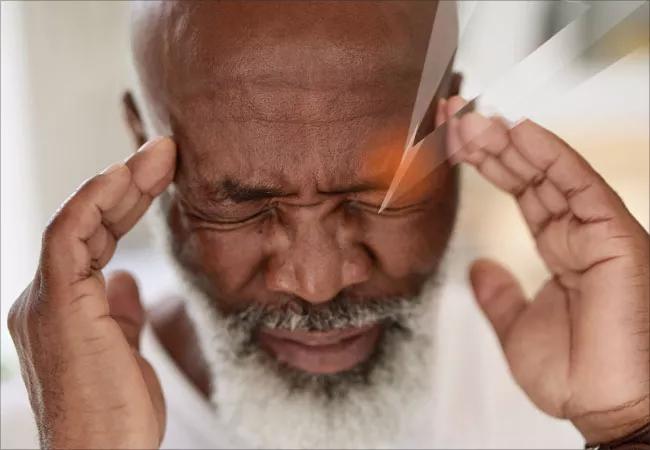 Man touching fingers to the sides of his forehead in distress and pain.