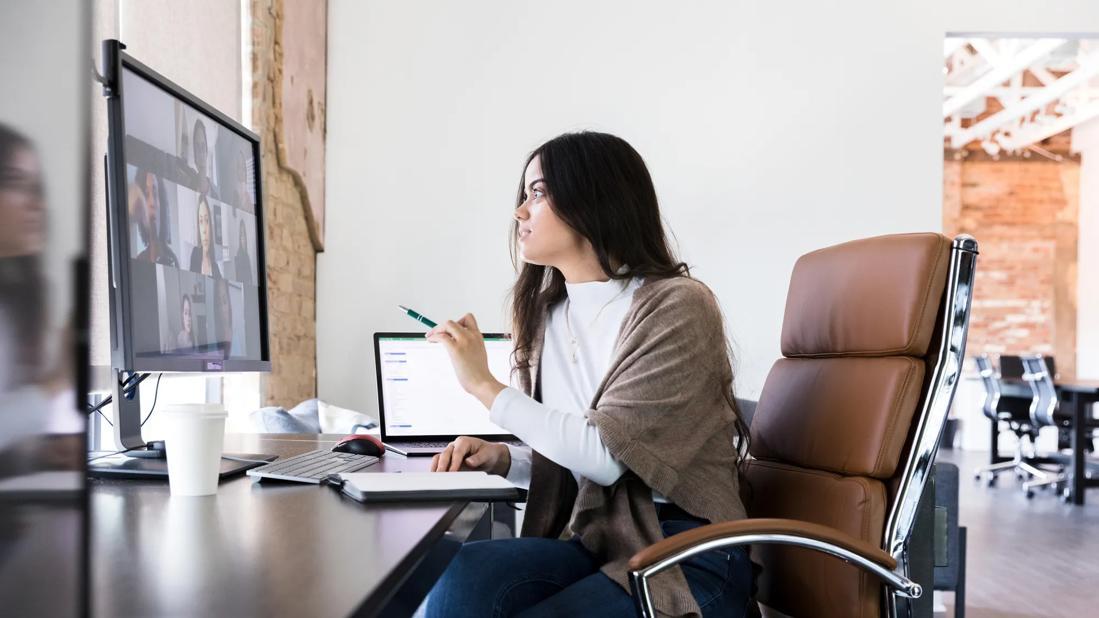 Person seated at office desk chair while on a virtual team call