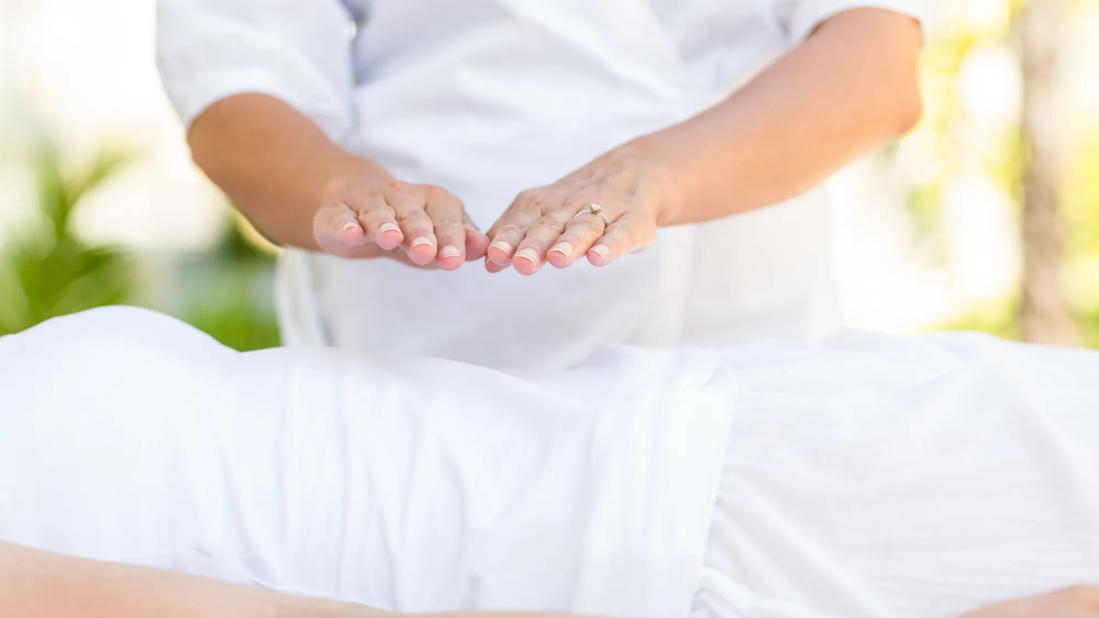 Reiki being performed by practitioner, with hands hovering person's abdomen