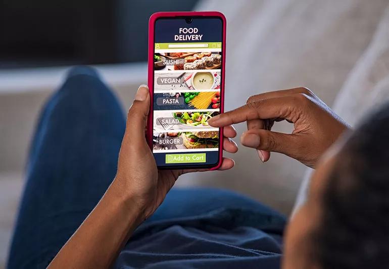 Person making a selection from a food delivery app on their phone.