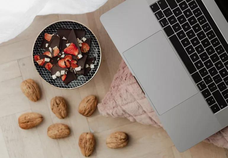 Snack of chocolate, strawberries and walnuts by laptop