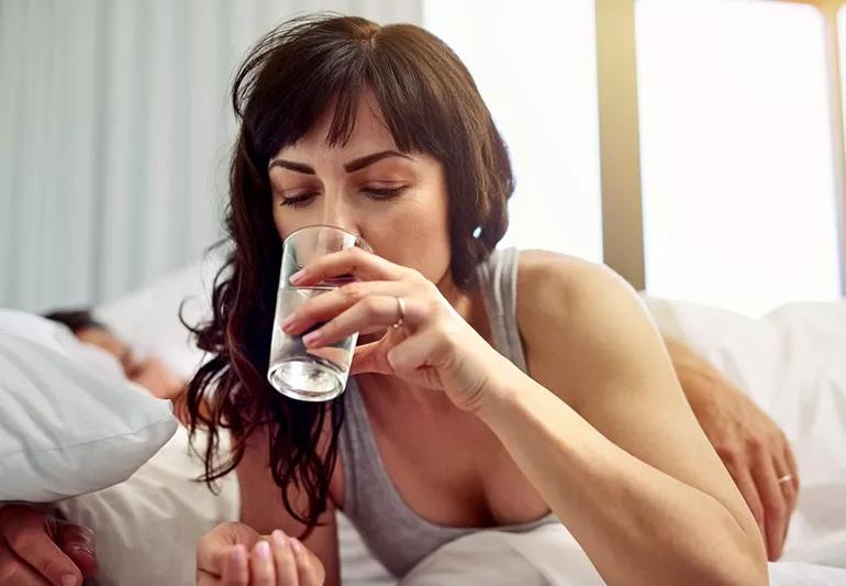 Woman taking medication while in bed