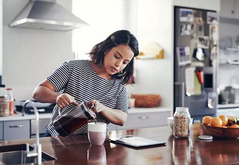 Person pouring coffee in kitchen from a French press.