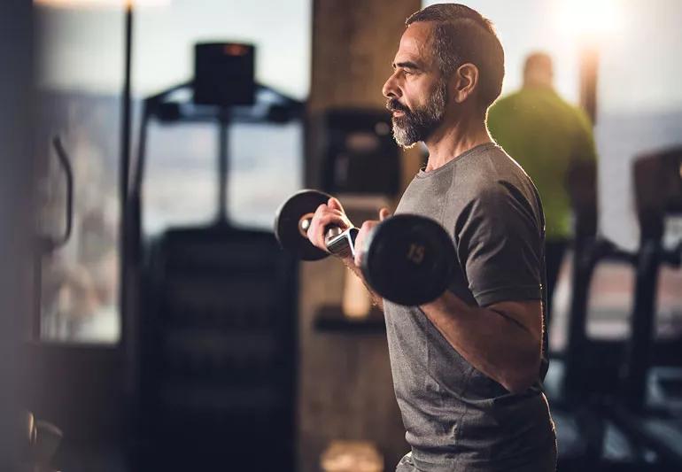 Fit senior man lifting weights in gym