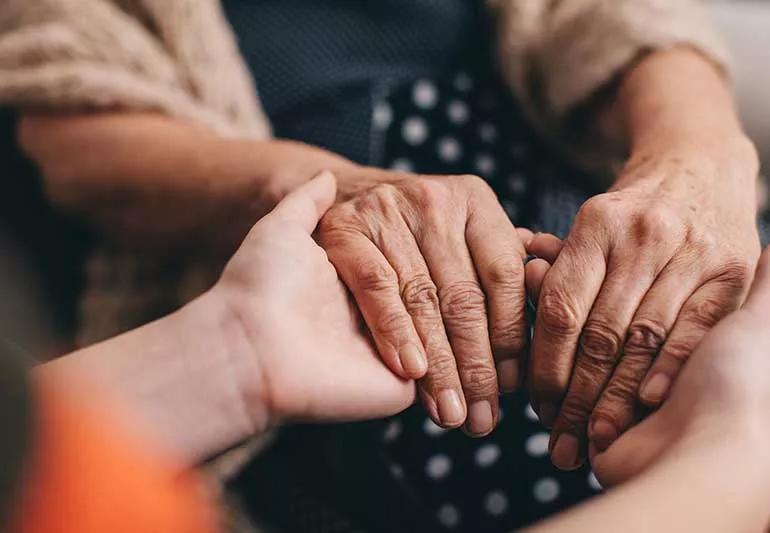 Someone holding an elderly persons hands.