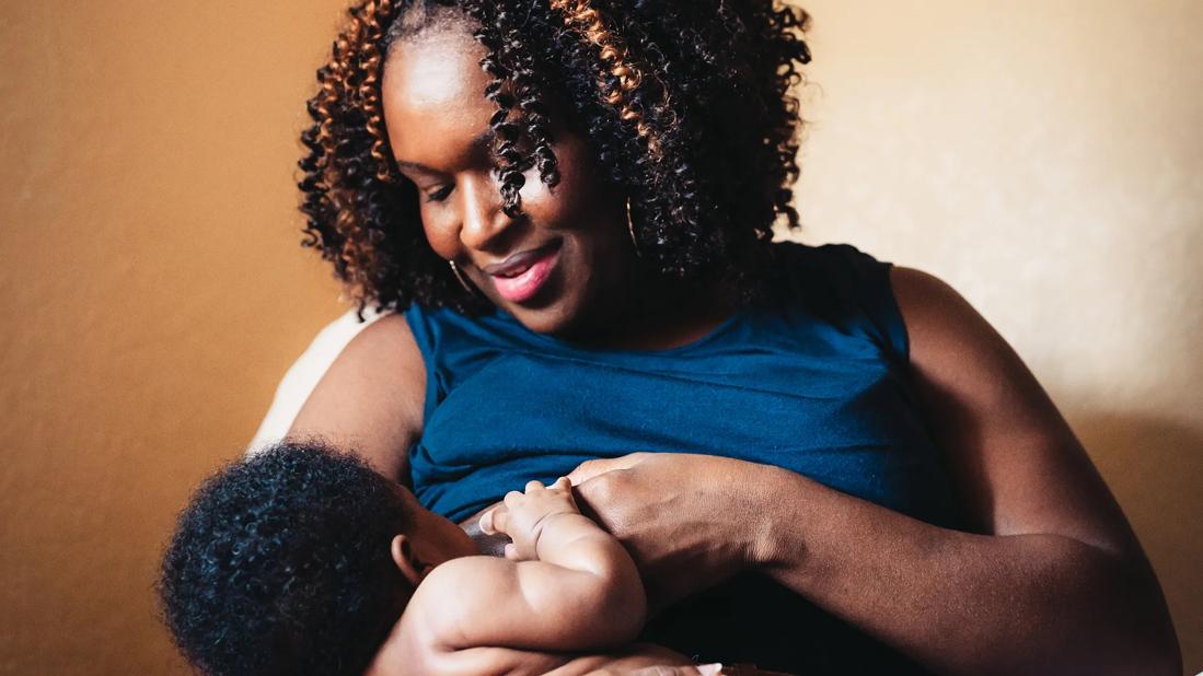 Smiling mother looking down on baby breastfeeding