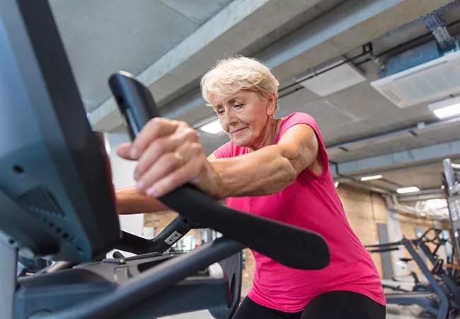 Senior woman exercising on cycling machine at rehabilitation gym