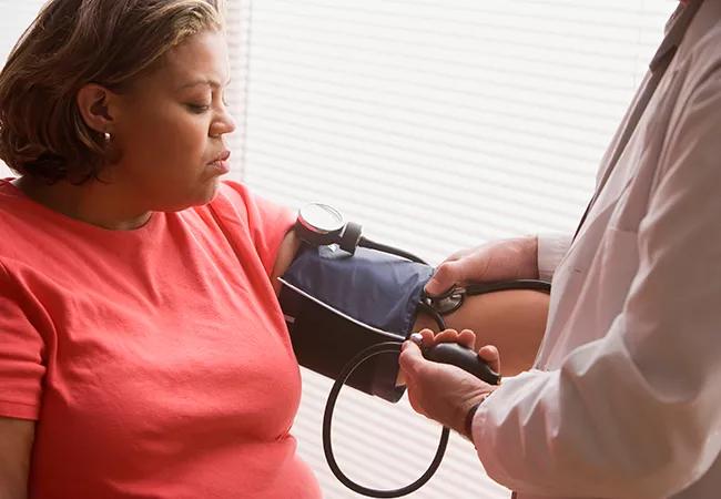 Middle-aged overweight Hispanic woman having her blood pressure checked