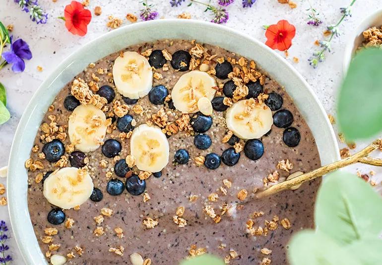 A bowl of blueberry smoothie topped with blueberries and cut banana