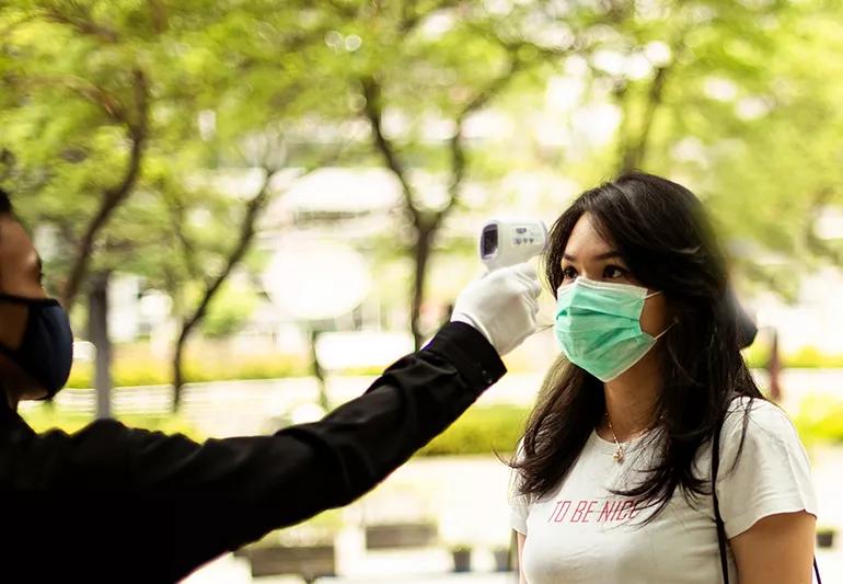 Woman having her temperature taken with infrared thermometer