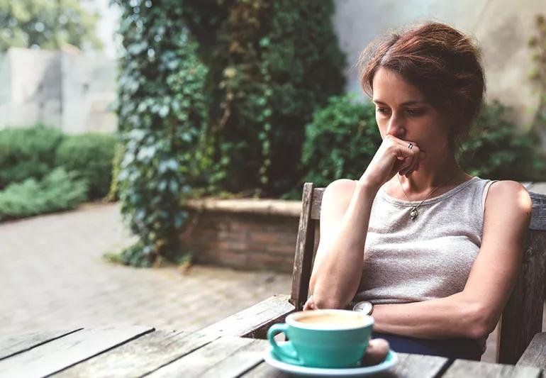 Woman sitting on porch and contemplating onset of early menopause