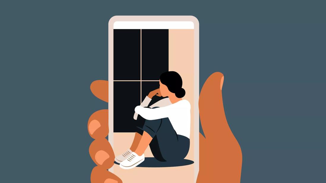 Someone holds up a smartphone and on the screen, there's a picture of a sad person looking out a window.