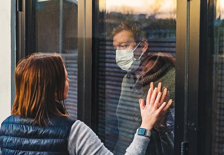 Man in self-imposed quarantine communicating with wife through window