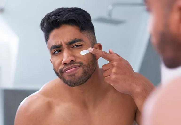 Applying moisturizer to clean skin in his morning bathroom routine.