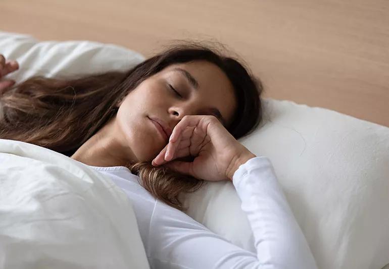 A person has fallen fast asleep while laying their head on a pillow.