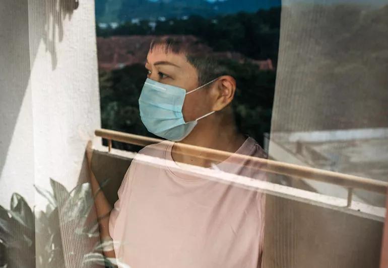 woman looking out of window during self quarentine