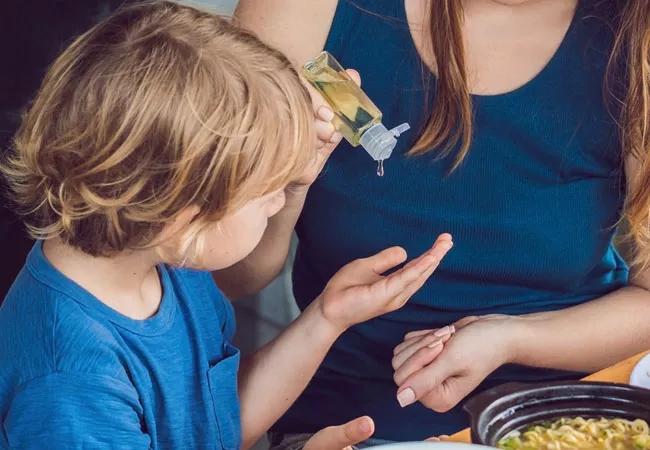 woman giving a child hand sanitizer