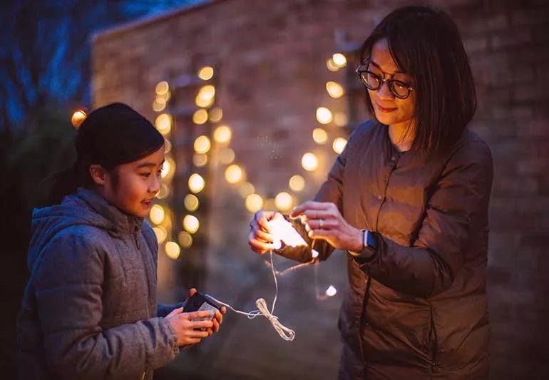 Parent and child untangling holiday lights.