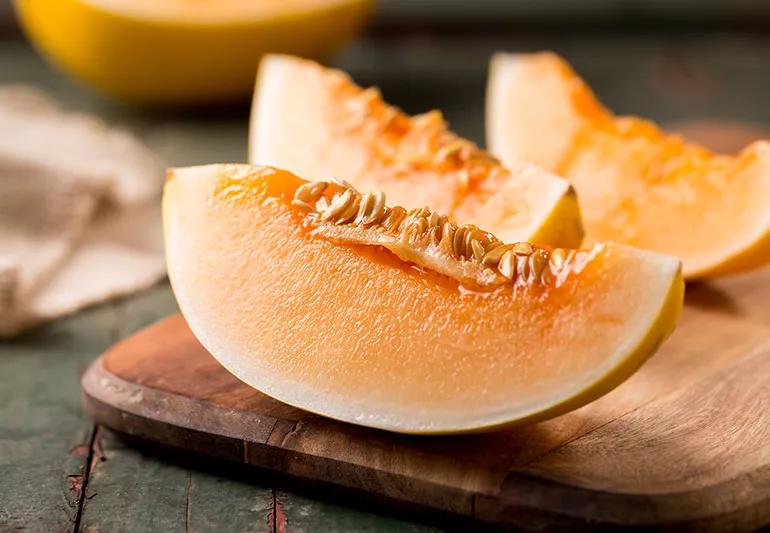 Cantaloupe slices sitting on a cutting board