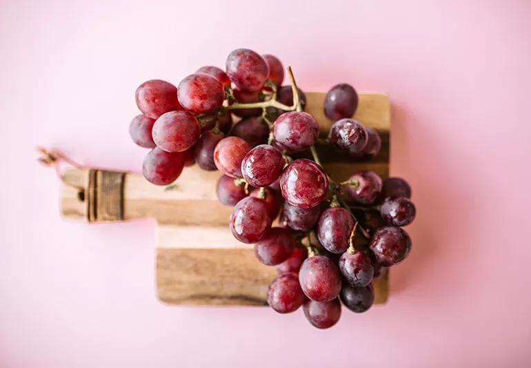 A bunch of grapes on a cutting board.