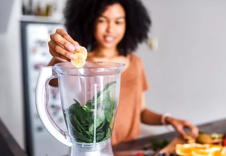 woman making a smoothie that includes bananas and spinach