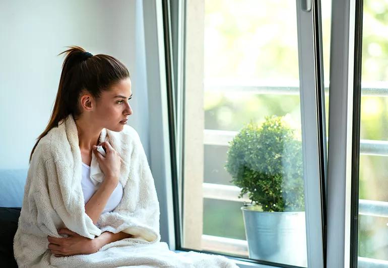 woman with sore throat sitting by open window