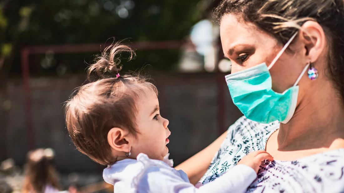 Single mother with pollution mask holding a baby