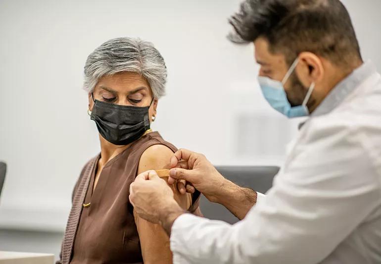 A doctor applies a Band-Aid to a patient's arm following vaccination