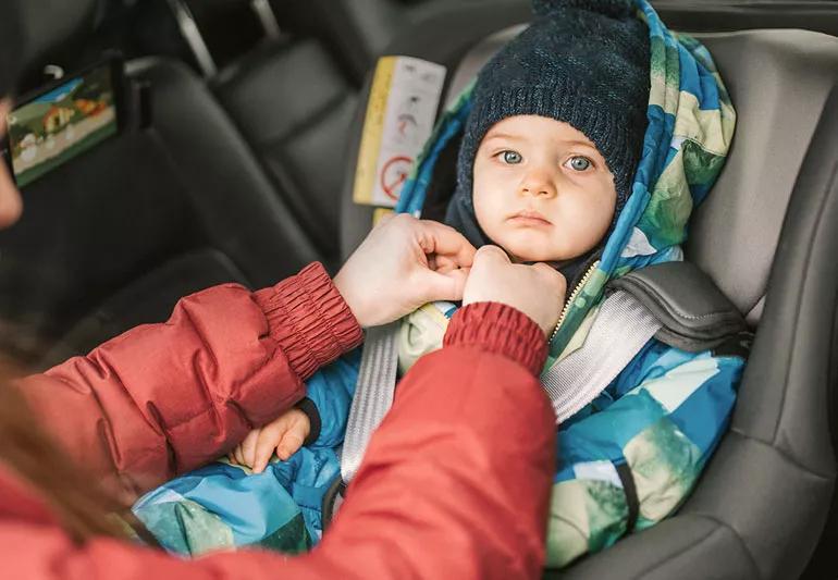 infant with puffy coat in getting put in care seat