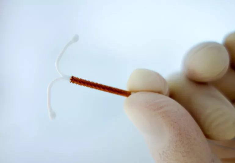 An IUD device held between two fingers
