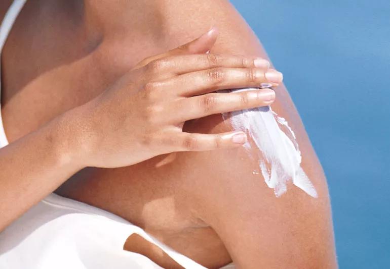 A person applying lotion sunscreen.